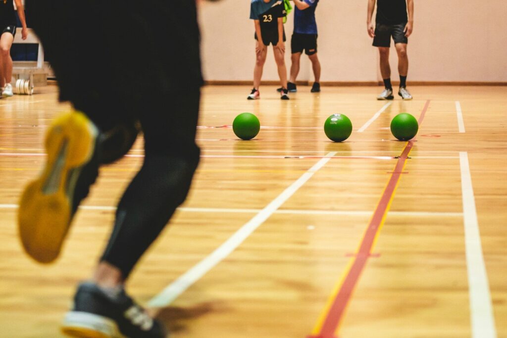 Jugadores de dodgeball en una pista con balones verdes