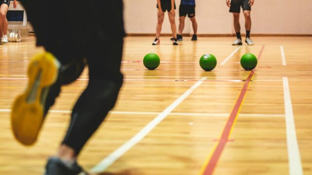Jugadores de dodgeball en una pista con balones verdes