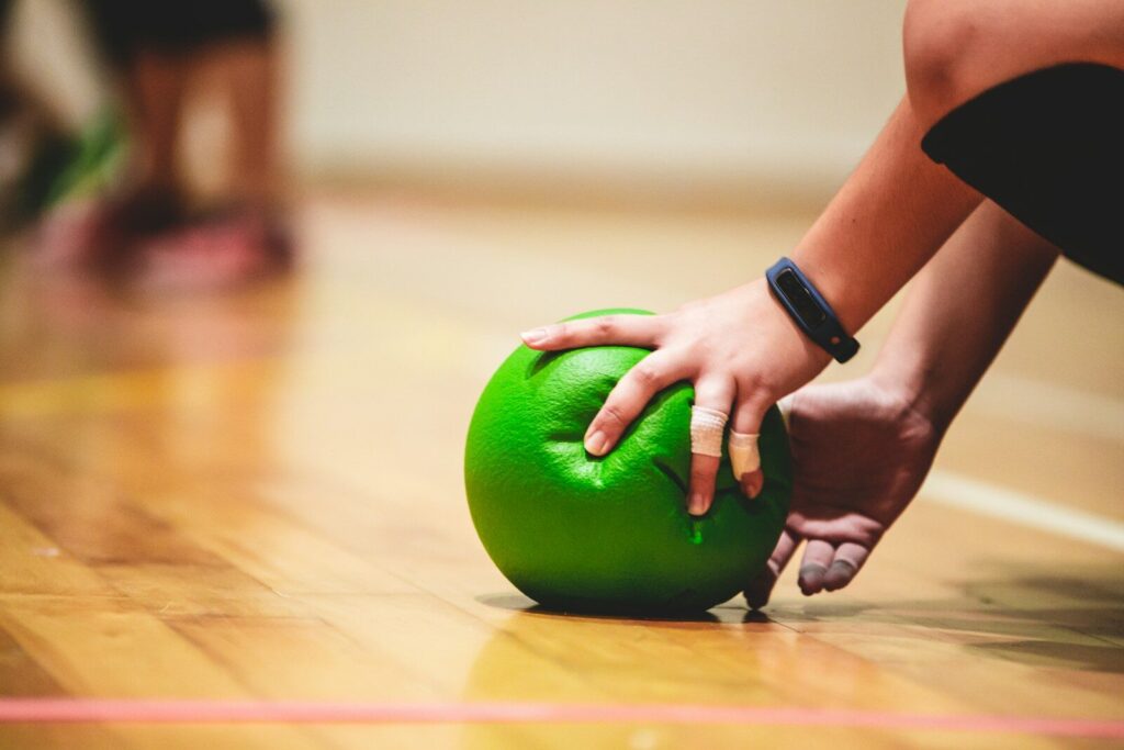 Mano sujetando un balón de dodgeball verde